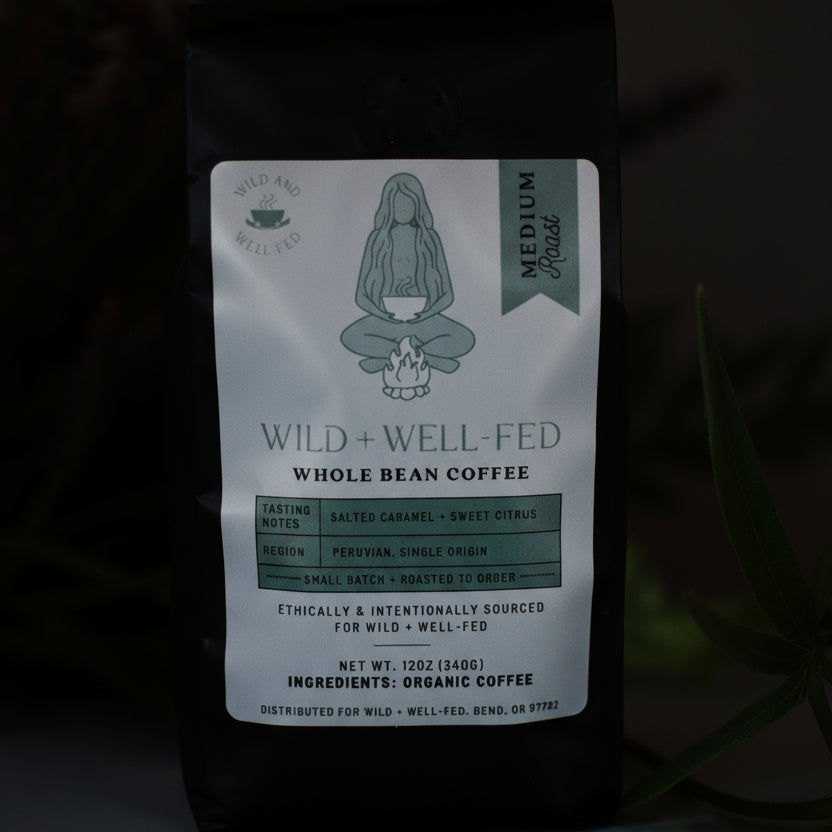 Wild + Well-Fed Medium Roast coffee from Peru, bag among green plants
