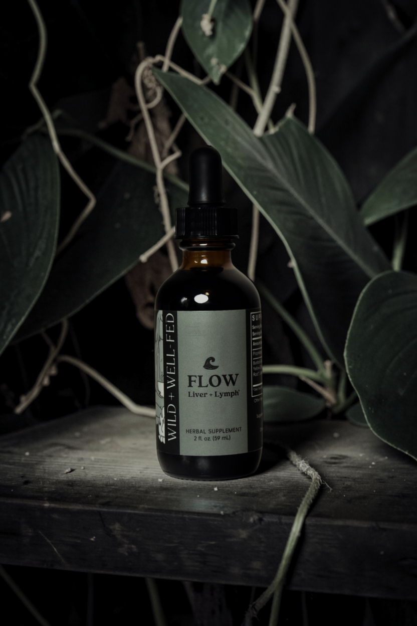 Bottle of 'Flow' supplement on a wooden surface with leaves in the background
