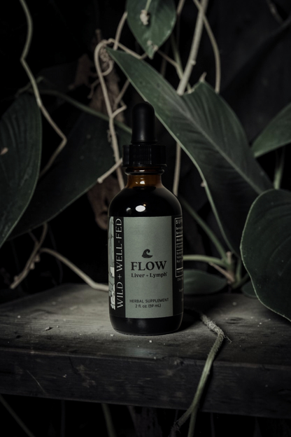 Bottle of 'Flow' supplement on a wooden surface with leaves in the background