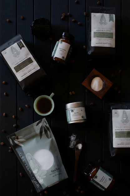 Collection of natural products including tea packages, a cup, and a jar on a dark surface.